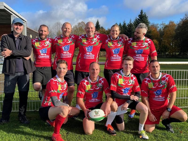 L'équipe de rugby à 5 en maillots rouges Ville de Chantilly, adultes réunis au bord du terrain.