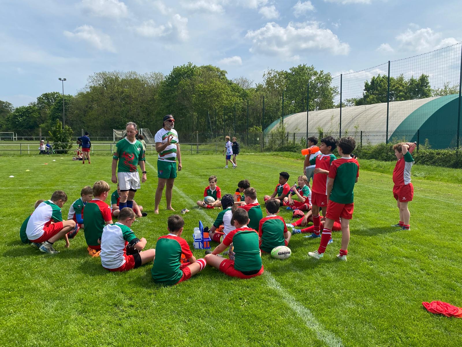 Groupe de joueurs U10-U12 réunis autour des éducateurs en bord de terrain