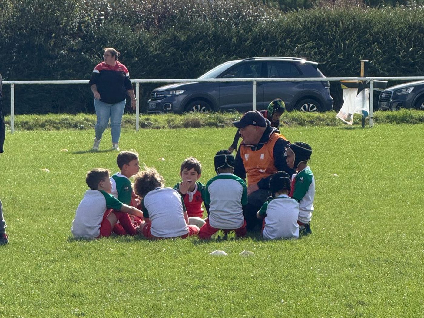 Groupe U10 en cercle avec l'éducateur, briefing sur le terrain